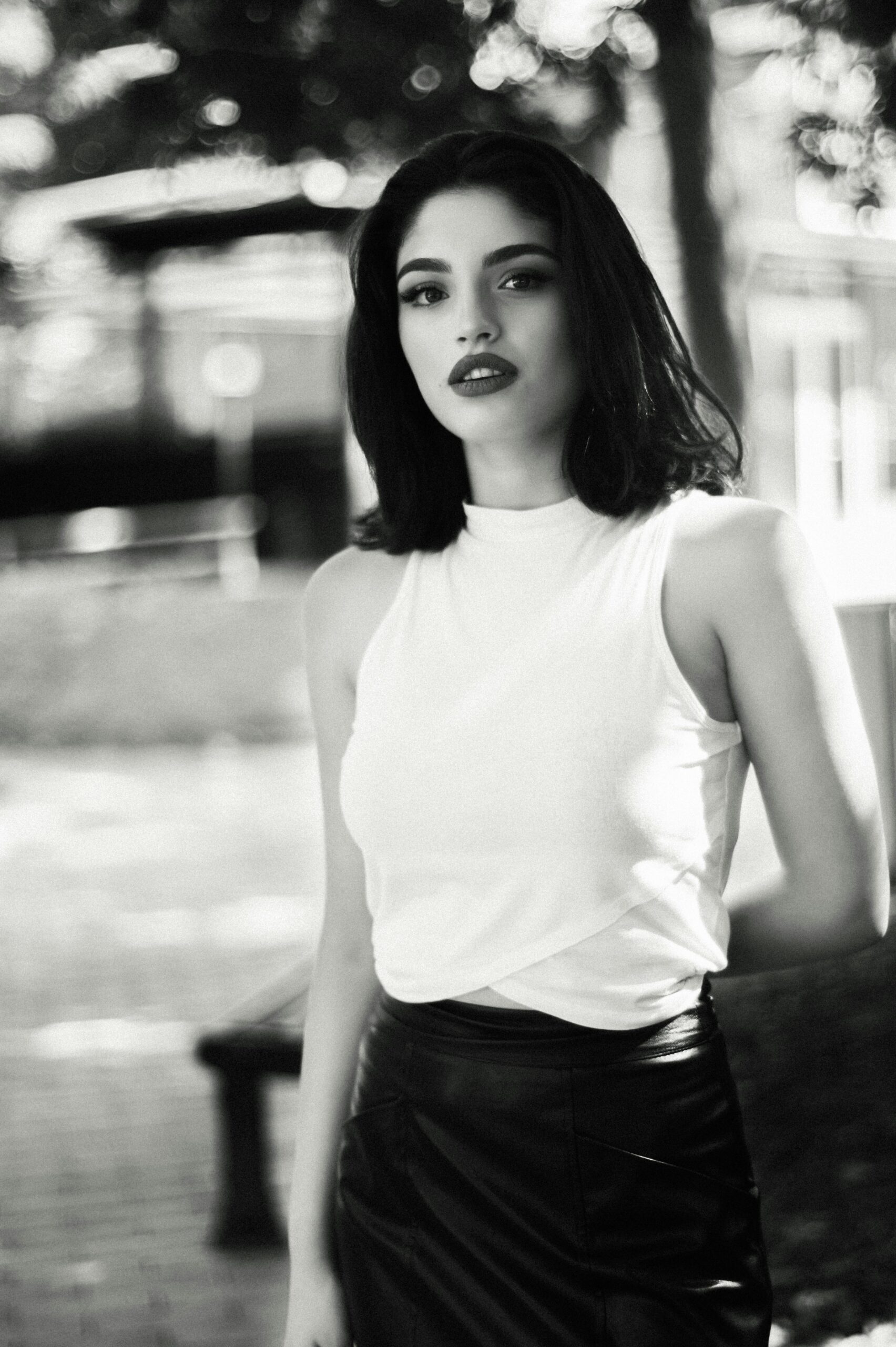 Monochrome portrait featuring a stylish woman outdoors with an elegant pose and natural lighting.