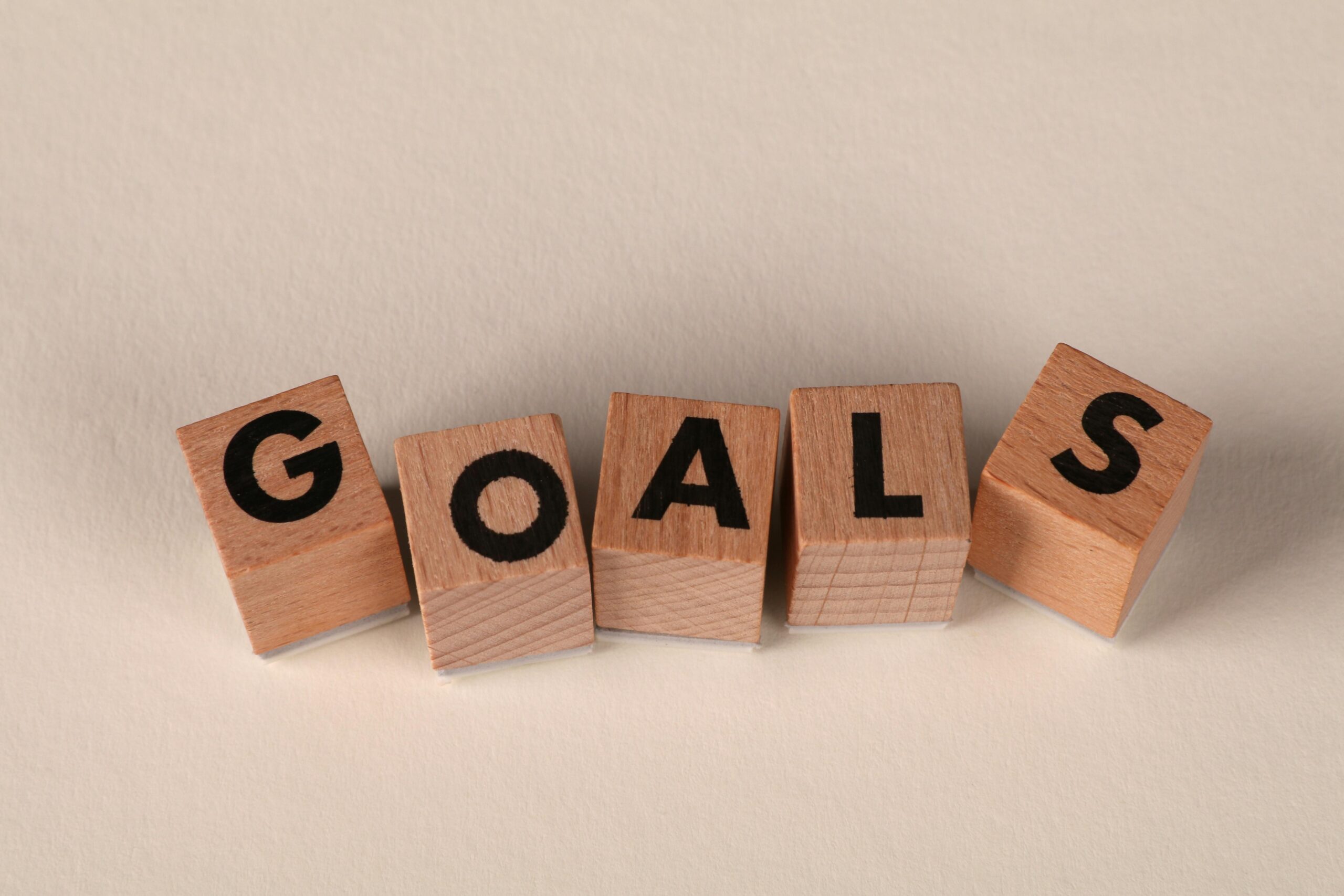 Aligned wooden blocks spelling 'Goals' symbolize target achievement and ambition.